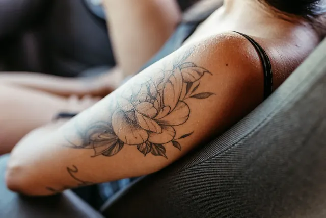 Fine line floral tattoo on an upper arm, healed