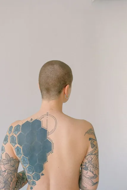 Lettering tattoo reading Freedom on the back of an back + arms, healed