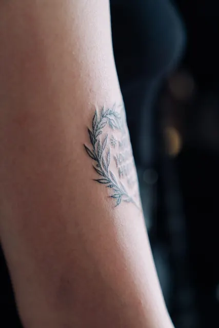 Fine line laurel branch with small lettering on the arm, healed